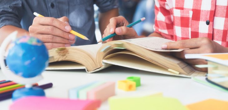 manos-de-jovenes-buscando-informacion-en-libros